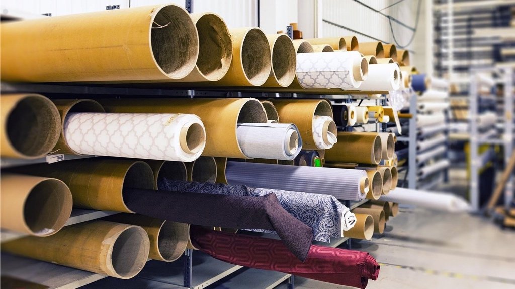Sürdürülebilir kumaş kaynağı ve doğru üretim yöntemini seçme Moda tasarımcısı kumaş rulolarını ve üretim seçeneklerini inceliyor